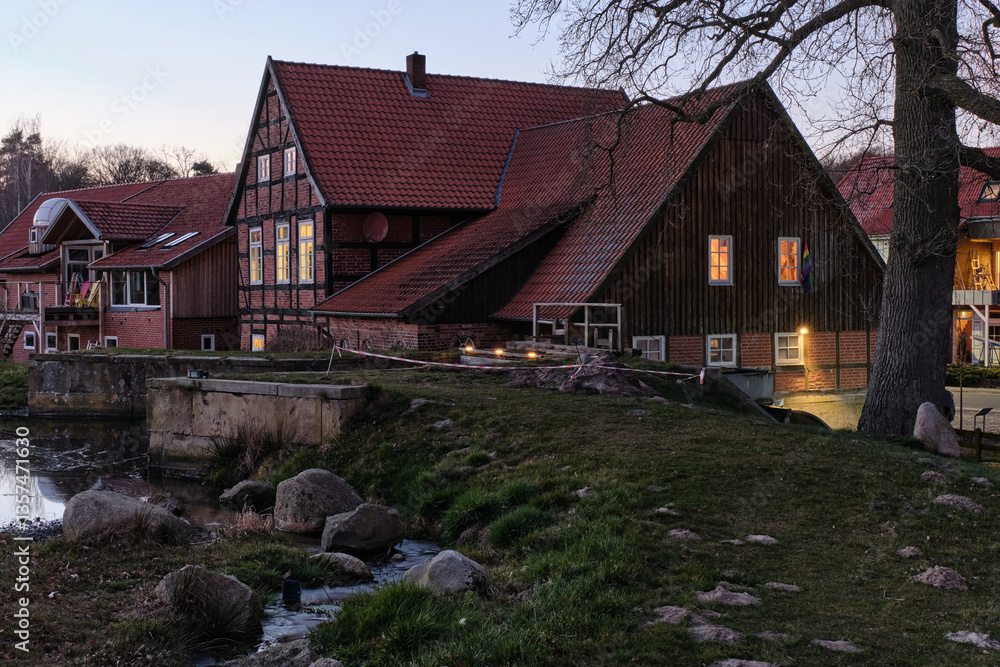 Fototapeta premium Bruchmühle in Bruchhausen-Vilsen, with half-timbered house, mill dike and tree at dawn