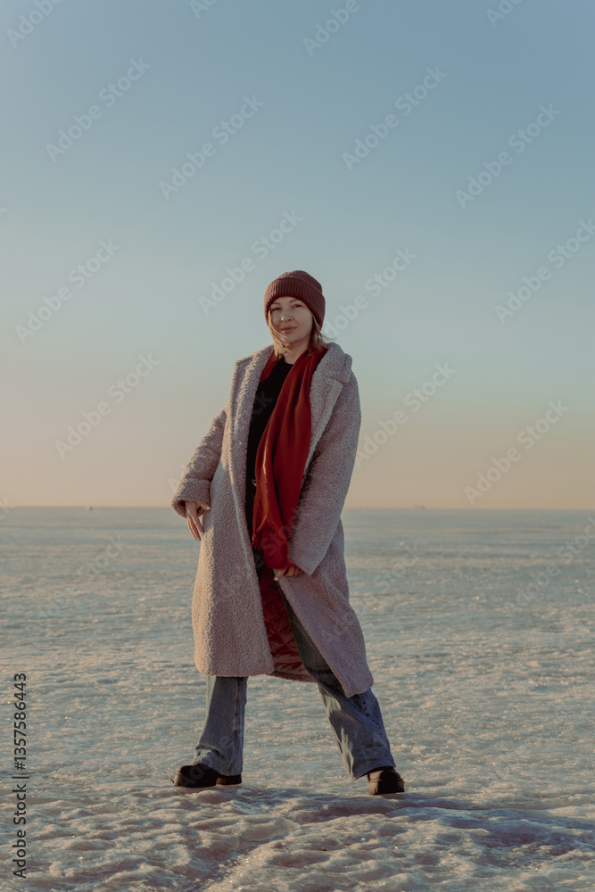Girl in coat in winter on the background of snow and ice at sunset Girl in coat in winter on the background of snow and ice at sunset
