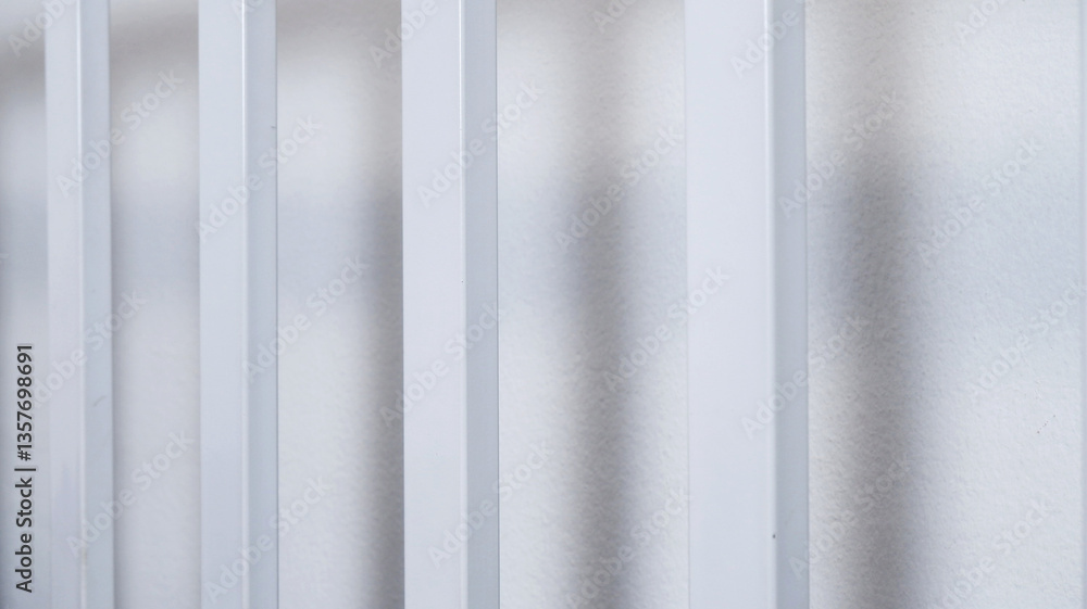 Fototapeta premium Iron rods with white wall background. Texture background of clean rod indoors with shadow. Concept of metal, hard object, material for interior, pipe, and equipment. Close-up straight steel rods.
