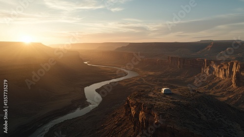 A breathtaking aerial view of a river winding through a canyon at sunset, with a solitary tent perched on the cliff's edge.