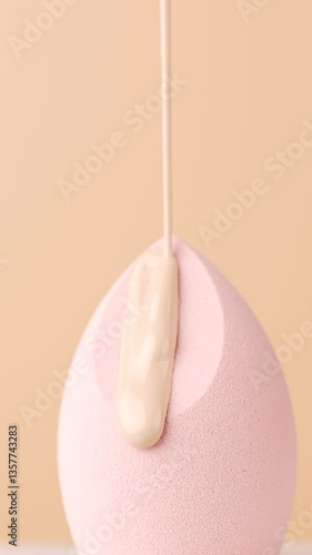 Hydrating Foundation falls on sponge. Cosmetic liquid foundation pouring on Beauty blender. Close up