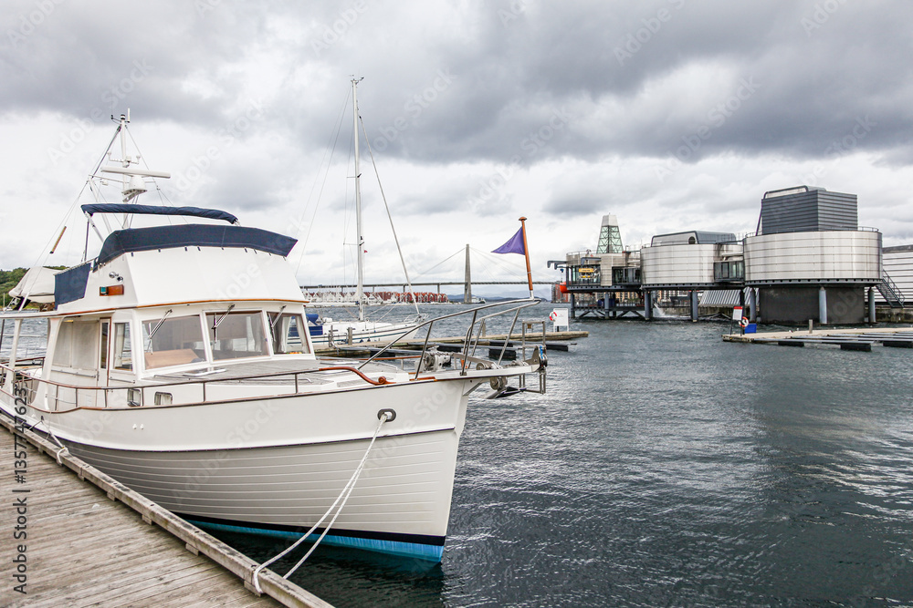 Fototapeta premium A boat is docked at a marina with a cloudy sky in the background and Norwegian Petroleum Museum in Stavanger in Norway