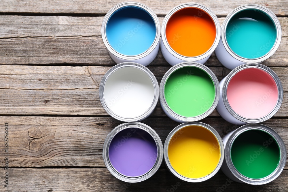 Fototapeta premium Cans of bright paints on wooden table, flat lay. Space for text