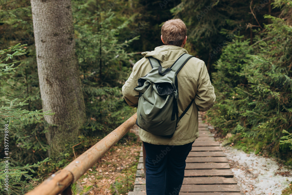 Young 30s man hiking in nature. Travel, adventure. Concept of an active lifestyle. High quality photo. Back view. Fall autumn hiker man outdoor at nature forest