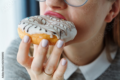Close-up of a woman's mouth eating a donut with glazed chocolate