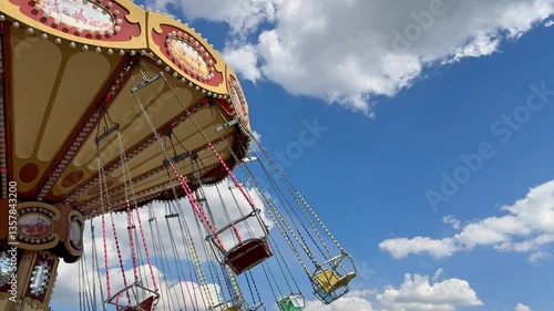 Vintage-style flying swing carousel spinning under a sunny sky. This classic fairground attraction evokes childhood memories, fun, and joy at theme parks and carnivals