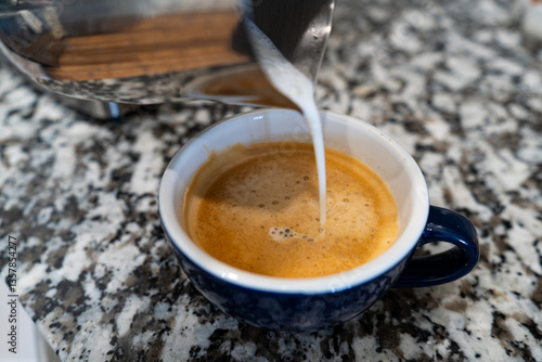 Pouring Milk Into a Cup of Espresso Coffee