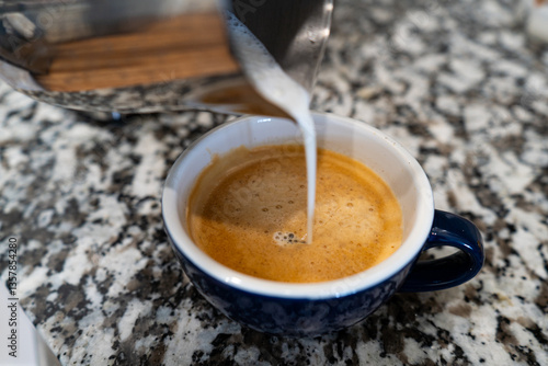 Pouring Milk Into a Cup of Espresso Coffee