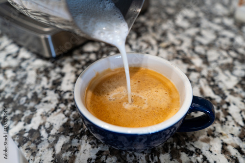 Pouring Milk Into a Cup of Espresso Coffee