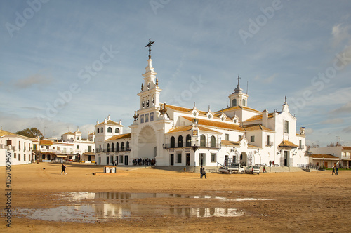 Historic white Virgin of Rocio sanctuary church with ornate towers in an open sandy plaza
