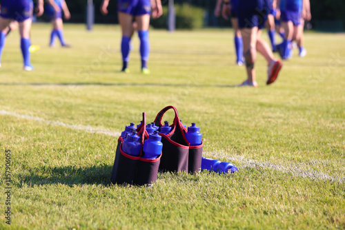 Sport bottles of fresh water energy drink on football rugby field grass