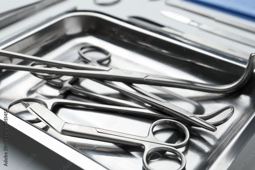 Different surgical tools in metal tray on light background, closeup Different surgical tools in metal tray on light background, closeup