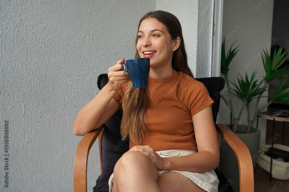 Brazilian young woman drinking a coffee sitting relaxed on balcony at home