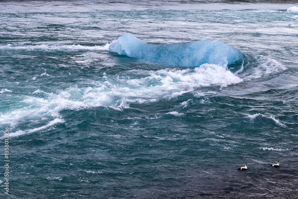 Fototapeta premium Iceberg floating on turquoise water in Iceland, creating small waves