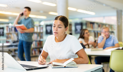 Smart female American student preparing for the exam in the school library