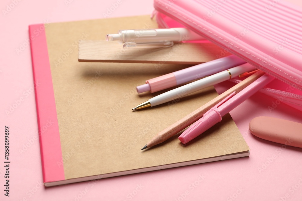 Copybook and other different stationery on pink background, closeup Copybook and other different stationery on pink background, closeup