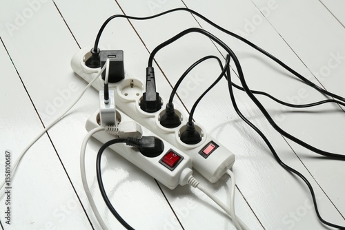 Extension power boards overloaded with plugs on wooden floor