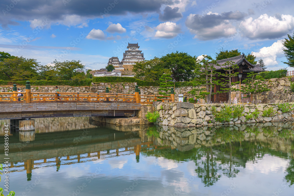 Fototapeta premium Himeji, Japan - Sep 24 2024, panoramic view of pond, bridge in front of fortress wall with gates of Himeji Castle, White Heron Castle, with castle itself in background, at daytime, Himeji, Japan