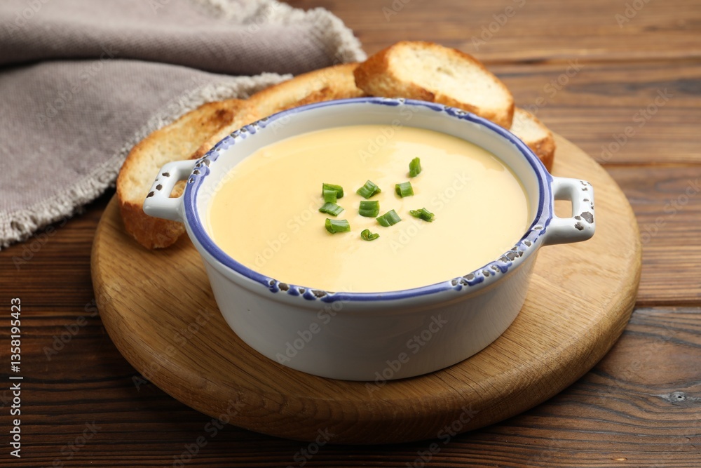 Tasty cheese dipping sauce in bowl and croutons on wooden table, closeup Tasty cheese dipping sauce in bowl and croutons on wooden table, closeup