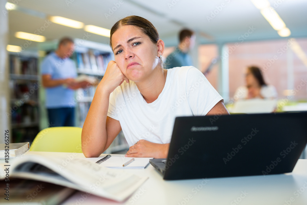 Portrait of upset tired female student in public library Portrait of upset tired female student in public library
