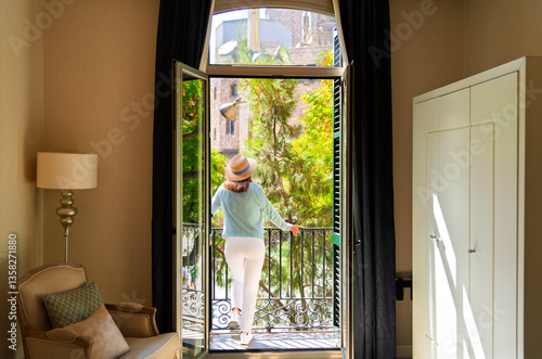Photography A young woman stands on a private balcony overlooking the historic medieval cathedral square in Barcelona, Spain