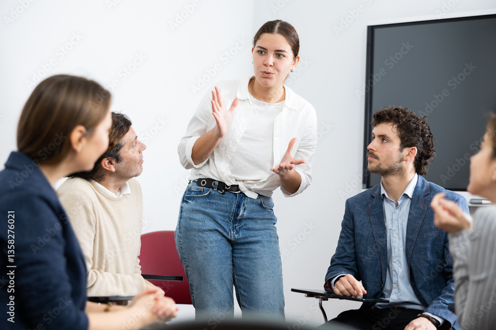 Fototapeta premium Young female teacher giving lecture to group of student