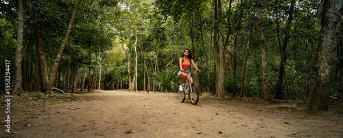 Toma panorámica de una mujer latina hermosa montando en bicicleta en un sendero de la selva/jungla, en México