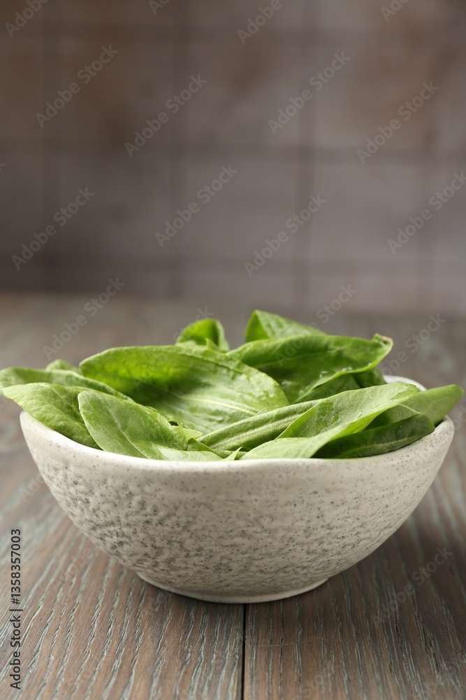 Fresh green sorrel leaves in bowl on wooden table, closeup Fresh green sorrel leaves in bowl on wooden table, closeup