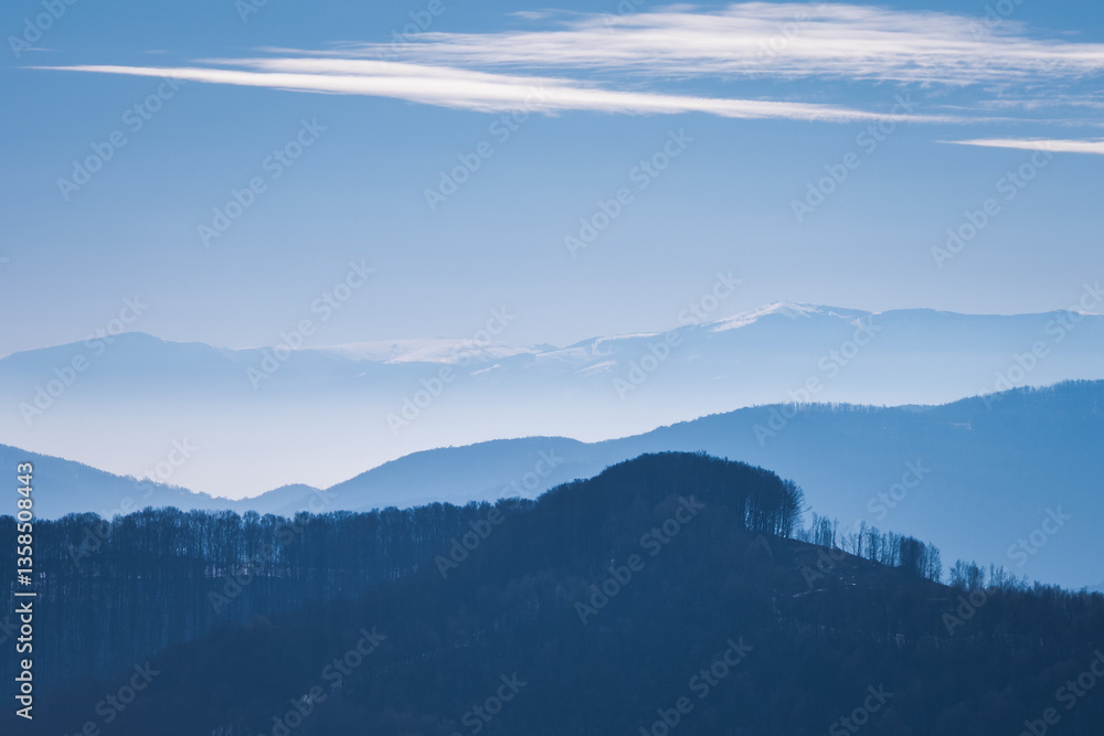Obraz premium Blue landscape with silhouettes of mountains and hills.