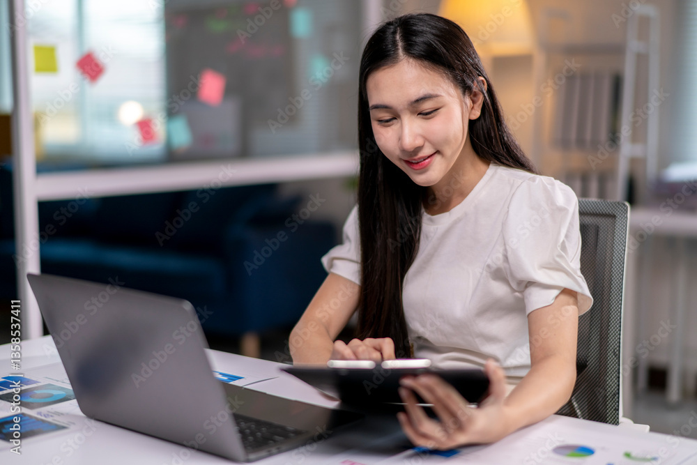 A woman is sitting at a desk with a laptop and tablet in front of her A woman is sitting at a desk with a laptop and tablet in front of her