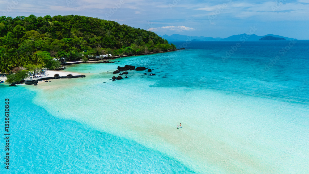Fototapeta premium Explore the breathtaking beauty of Koh Kham Island Thailand, where soft sands meet crystal-clear turquoise waters. This tropical paradise invites relaxation and adventure under a clear sky.