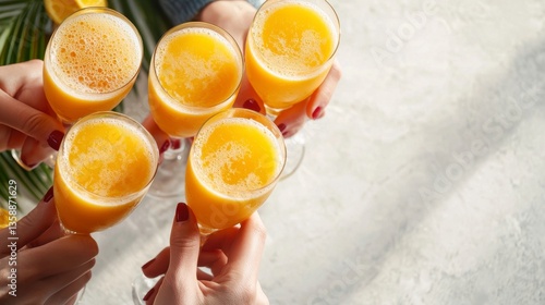 Stylish group of friends holding glasses filled with orange juice in a joyous toast for a memorable moment