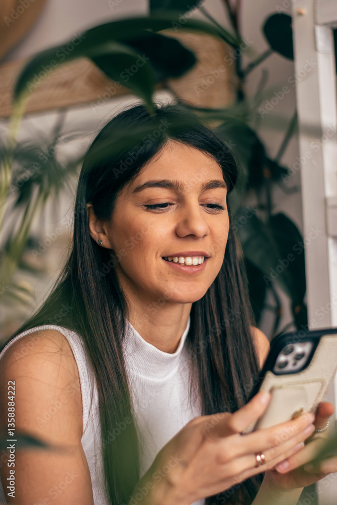 A smiling young dark-haired woman using a smartphone, close-up.