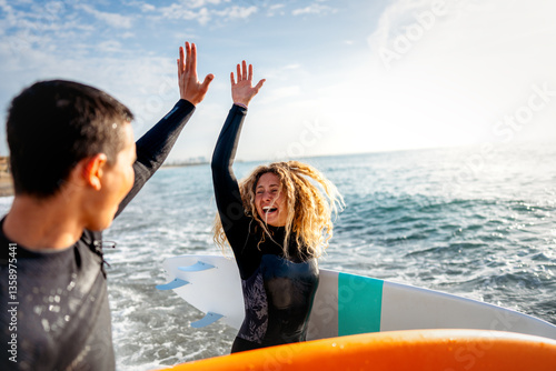 Foto Young beautiful couple of friends on the sea with surfboards in their hands, spo