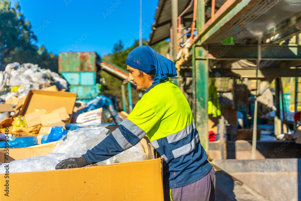 Fototapeta premium Worker separating materials outside a recycling plant