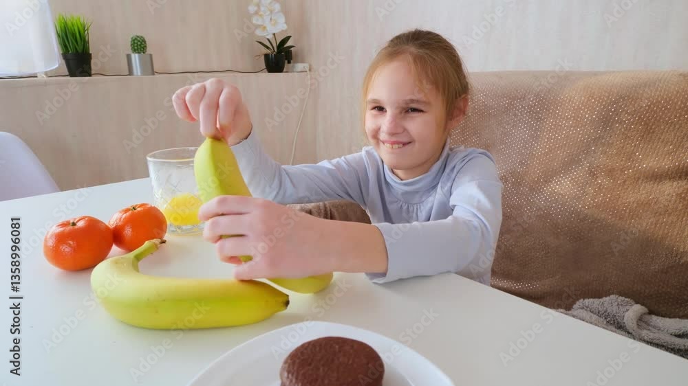 Little girl eating banana at the table at home Little girl eating banana at the table at home