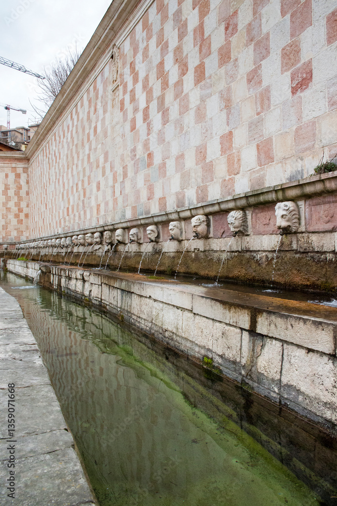Closeup of the square of the fountain of the 99 spouts (In Italian: Fontana delle 99 cannelle) located in the historic center of L'Aquila, in Abruzzo, Italy. It's a monumental fountain.