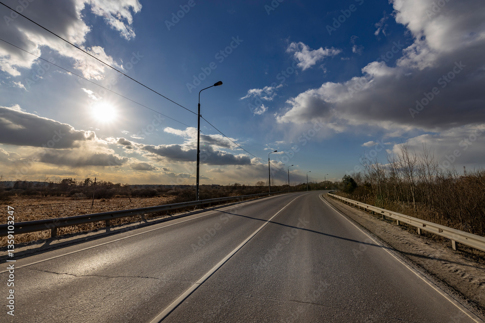 Fototapeta premium A road with a clear blue sky and a sun in the background