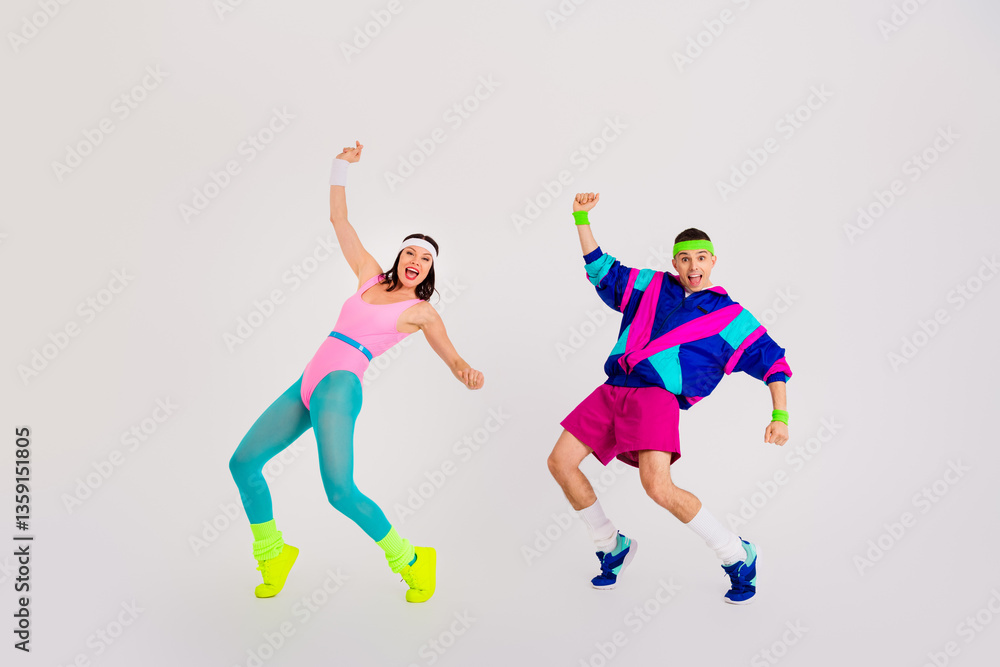 Obraz premium Energetic young couple enjoying a vibrant workout session in retro activewear against a white background