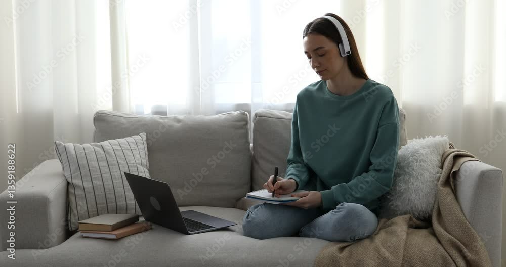 Woman learning online using laptop and taking notes on sofa indoors. Self-study Woman learning online using laptop and taking notes on sofa indoors. Self-study