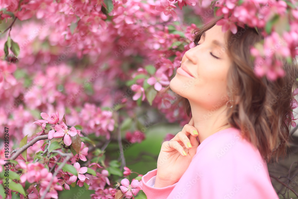 Fototapeta premium A woman in pink, in a cherry blossom garden in spring, a model posing, a soft spring photography