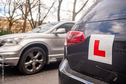 UK- Learner driver L plates attached to car on urban road in the UK