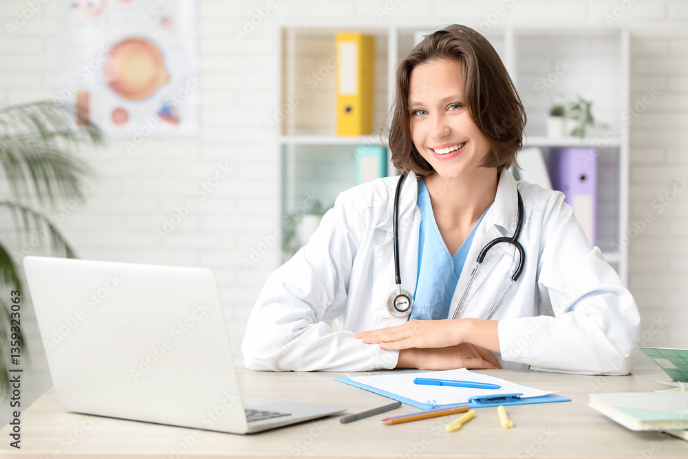 Beautiful female doctor with modern laptop and clipboard at table in clinic Beautiful female doctor with modern laptop and clipboard at table in clinic