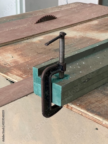 C-Clamp Securing Green Wooden Planks on a Rustic Workbench.