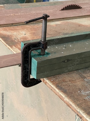 C-Clamp Securing Green Wooden Planks on a Rustic Workbench