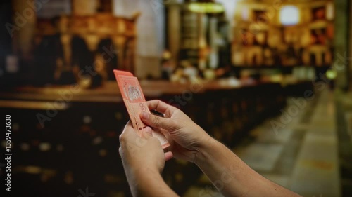 Hand holding malaysian ringgit indoors with blurred church interior suggesting a business or donation context.