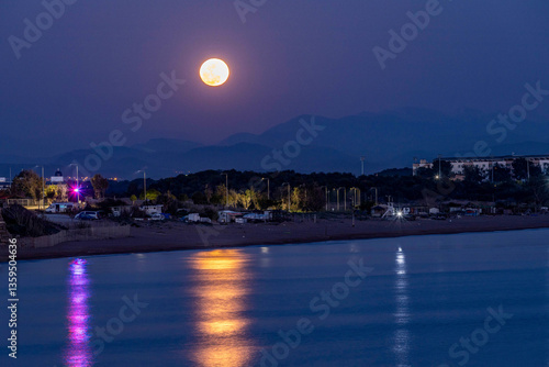 Fototapeta Naklejka Na Ścianę i Meble -  Rise of a huge full moon over the mountains. Moonlit path on the sea. Mediterranean, Side, Manavgat, Antalya province, Turkey