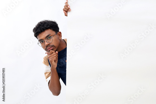 Funny curious asian man in blue apron peeking behind the wall