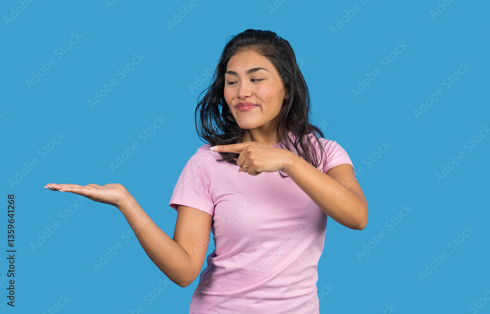 Fototapeta premium Young woman pointing at empty hand on blue background