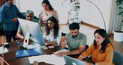 Indian Asian young business professionals, startup partners collaborating on an important project using computer, laptop in modern cozy office, discussing ideas, working together with full involvement